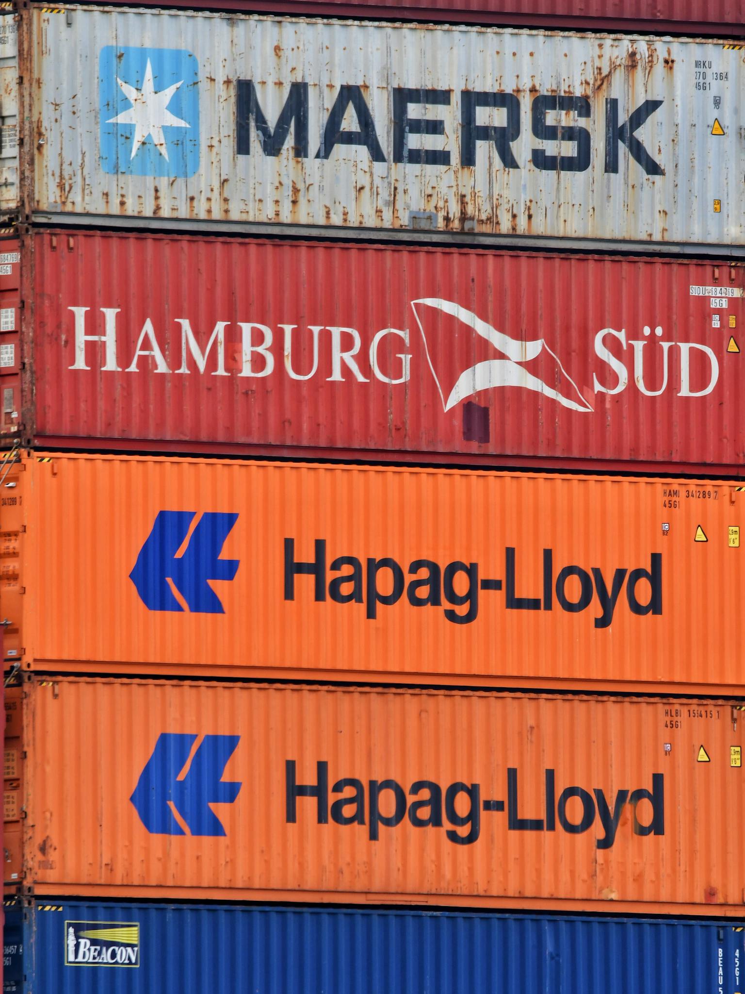 Close-up of stacked shipping containers featuring Maersk, Hamburg Süd, and Hapag-Lloyd logos.