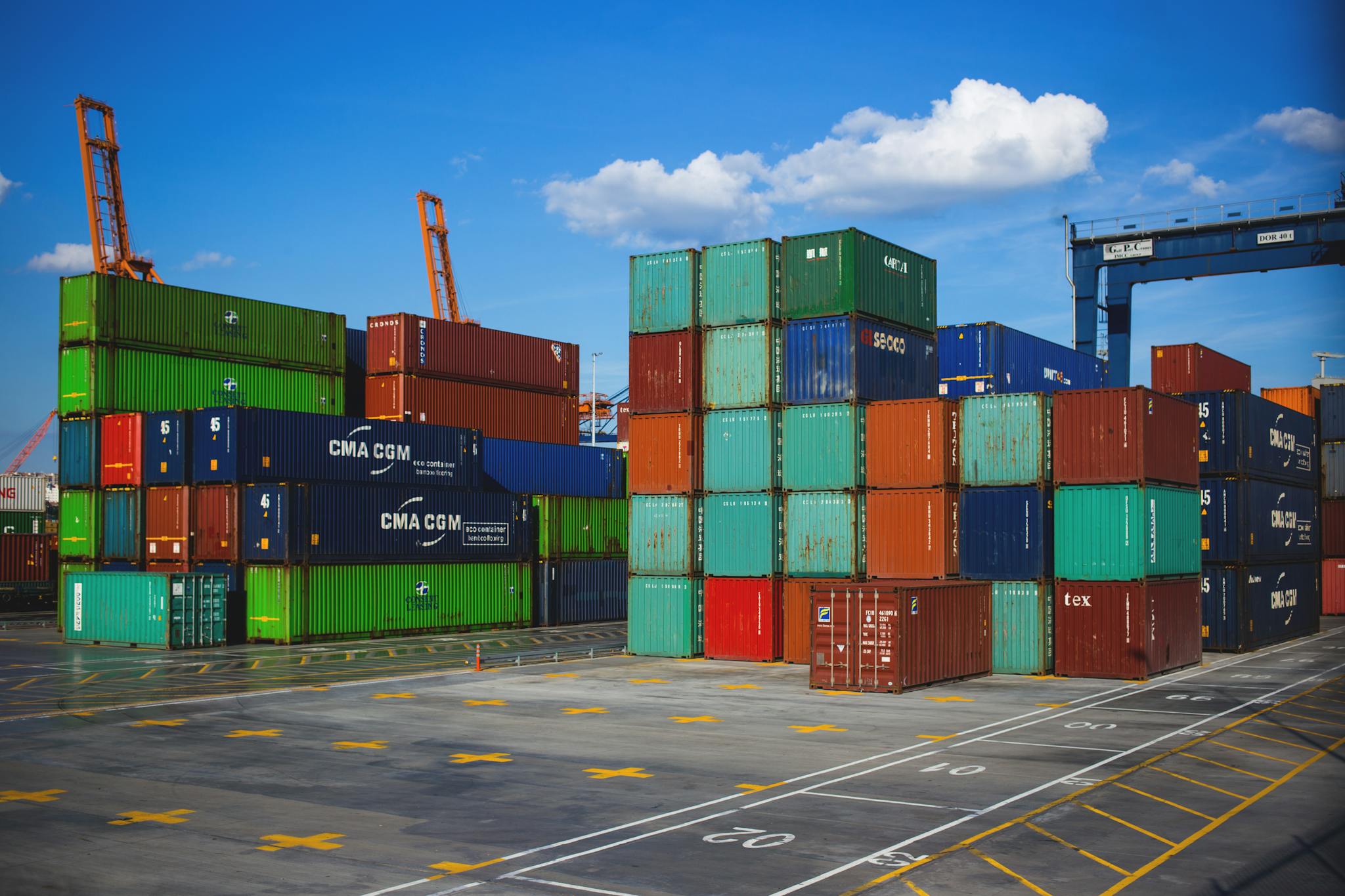 Vibrant shipping containers stacked at an industrial port under a blue sky.